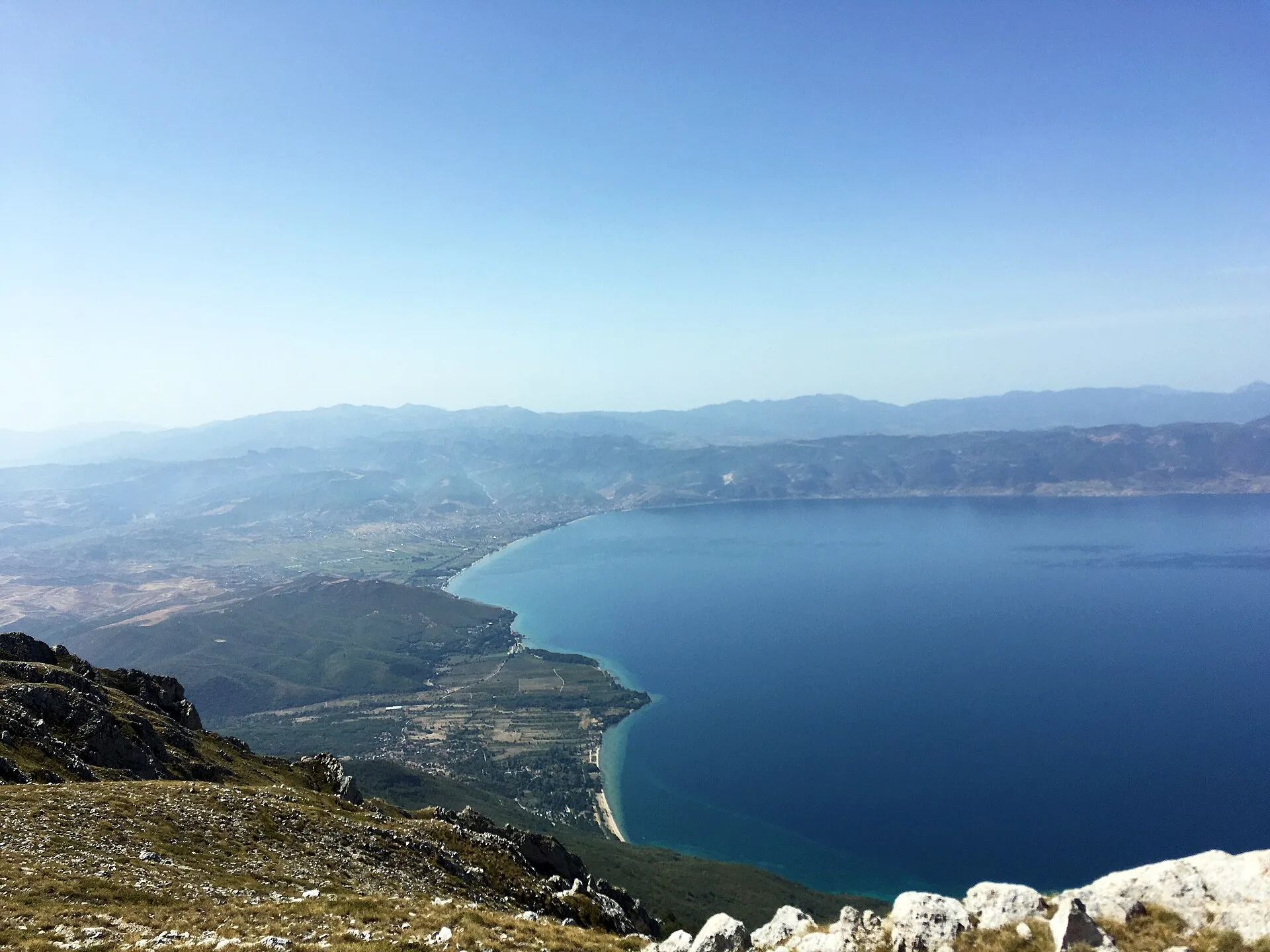 Panoramë e Pogradecit buzë Liqenit të Ohrit, me male dhe çati të kuqe